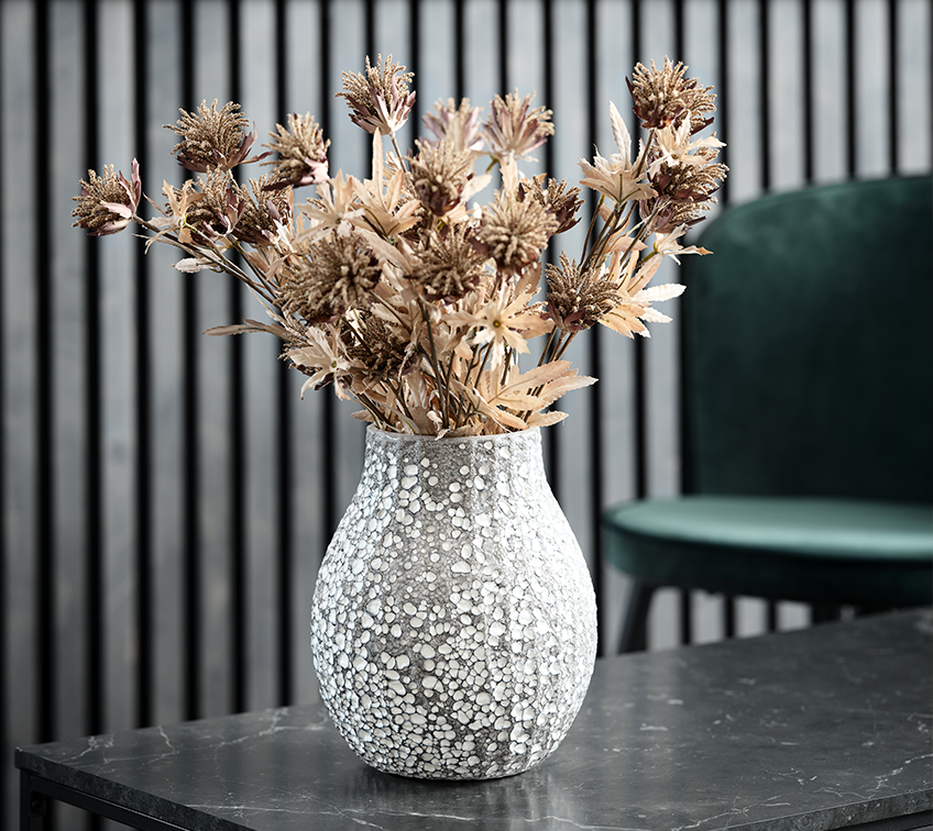 Срібляста ваза з коричневими штучними квітами у вітальні