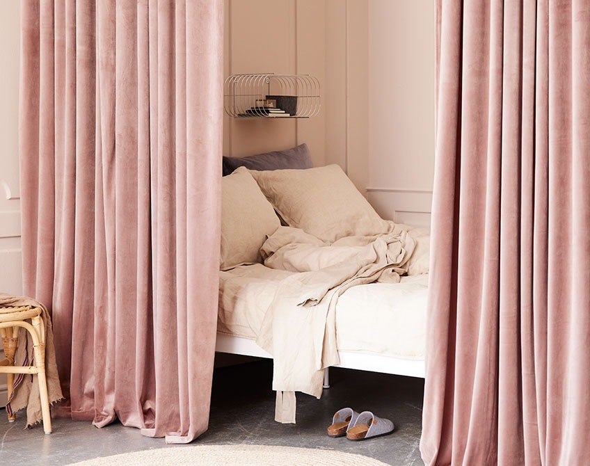 Рожеві штори, що використовуються для відокремлення спальної зони від великої вітальні