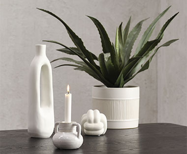 Білі декоративні елементи та білий квітковий горщик із зеленою штучною рослиною
