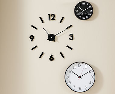 На стіні три годинники: з чорним циферблатом, з білим циферблатом та декоративний