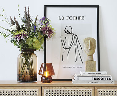 Фоторамка, що стоїть близько до стіни, ваза з квітами, декоративна статуетка і свічник