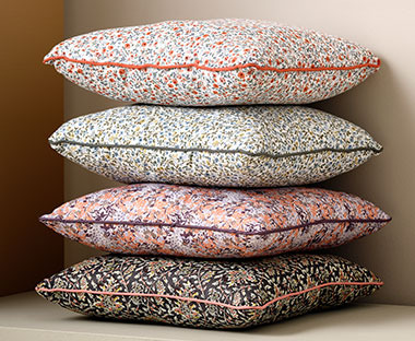 Чотири декоративні подушки з квітковим принтом складені одна на одній