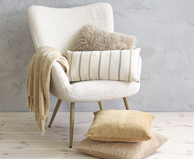 Світлі декоративні подушки на лляному білому кріслі