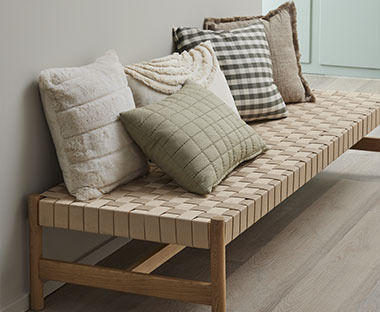 П'ять декоративних подушок різного дизайну на дерев'яній лавці