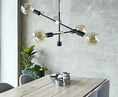 Індустріальна люстра з перехресними лампочками над столом