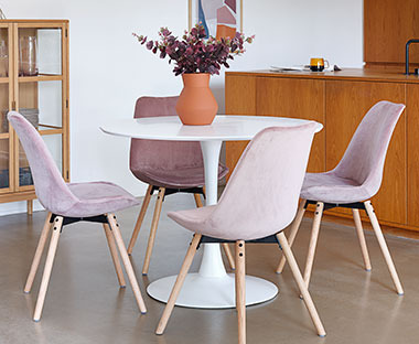 Круглий обідній стіл з рожевими стільцями на тонких ніжках