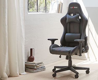 Чорне геймерське крісло зі зйомною подушкою для додаткової підтримки спини або шиї.