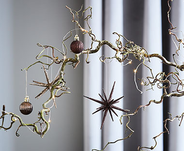 Новорічні кулі та декор у вигляді зірки, що прикрашають ялинкову гілку