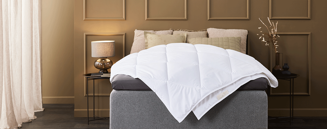 Світло-коричнева спальня з ліжком з декоративними подушками, ковдрою та топ-матрацом  
