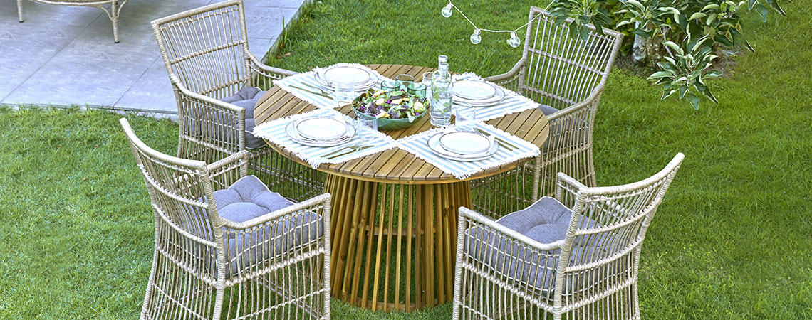 Круглий садовий стіл і чотири садові стільці на газоні 
