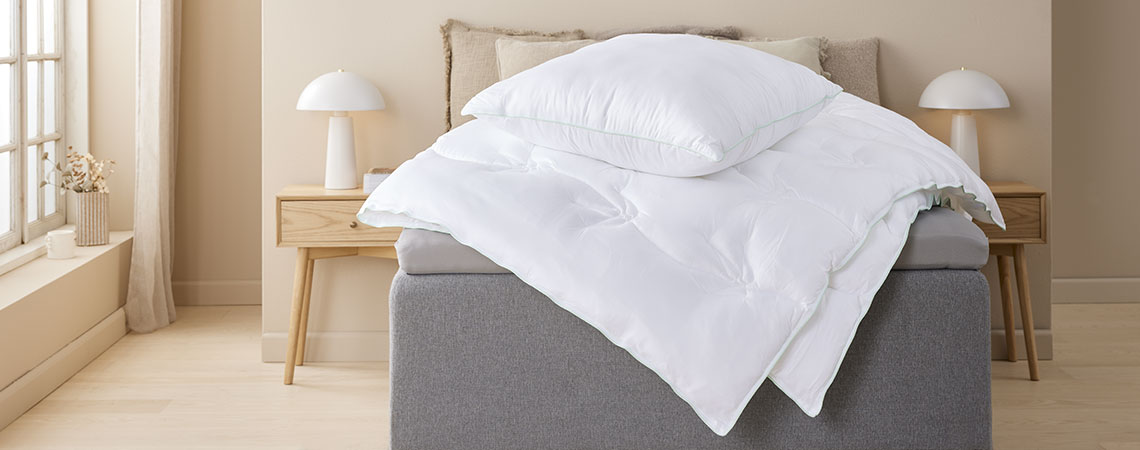 Ковдра і подушка з чохлом з бамбукової віскозної тканини на ліжку у світлій спальніI