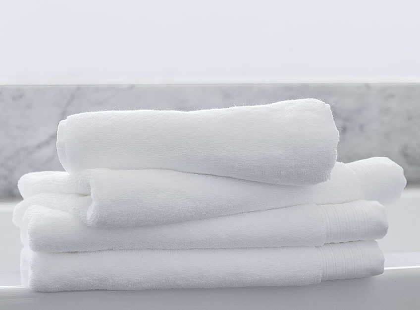 Білі рушники у ванній кімнаті складені стопкою