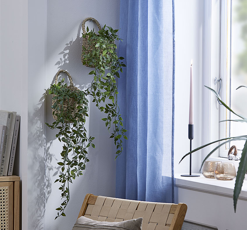 Два кошики зі штучними рослинами висять на стіні вітальні