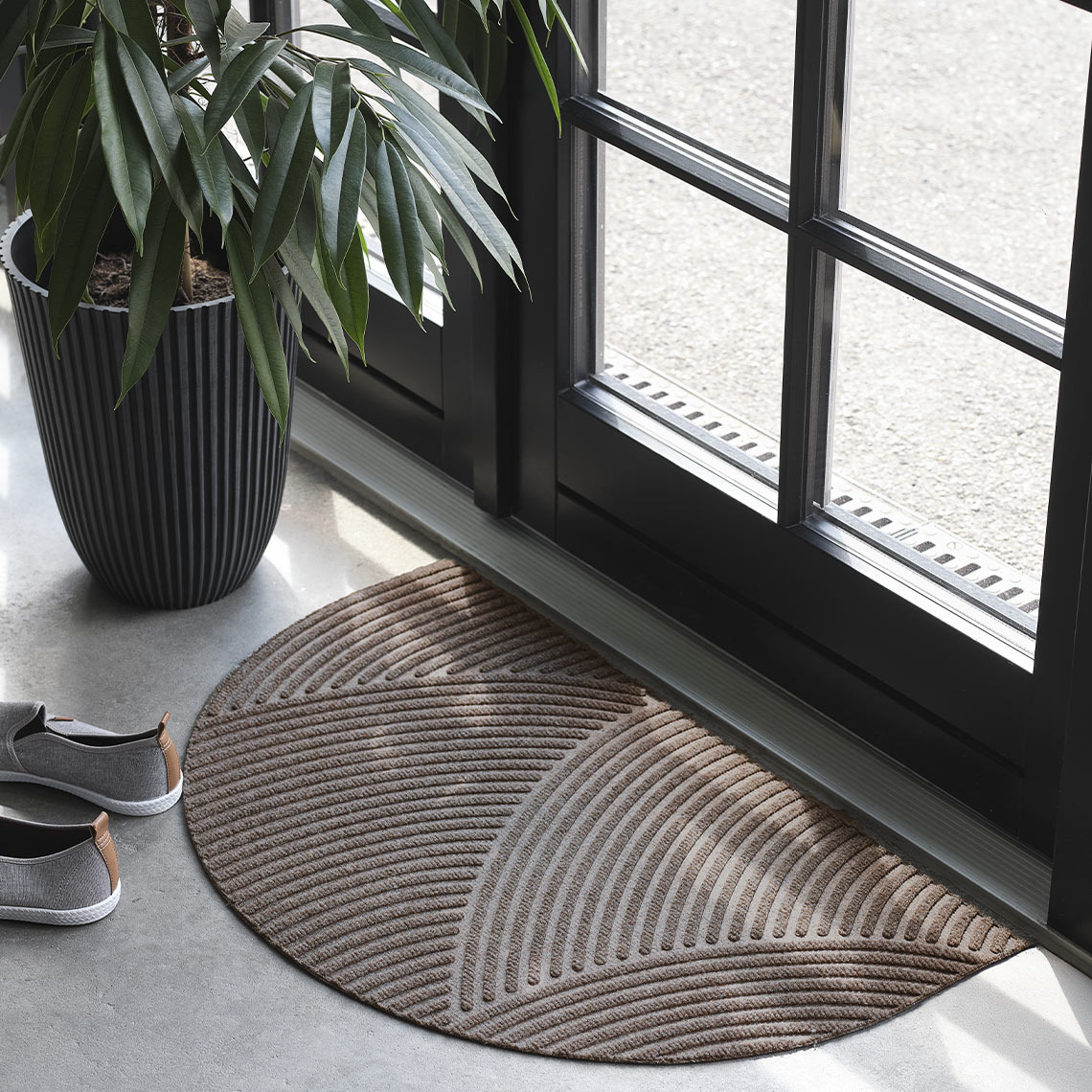 Коричневий напівкруглий придверний килимок на вході біля дверей