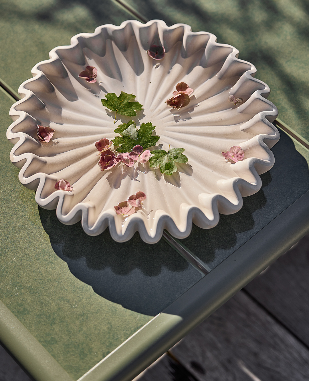 Купальня для птахів світлого кольору з квіточками та листочками на столі