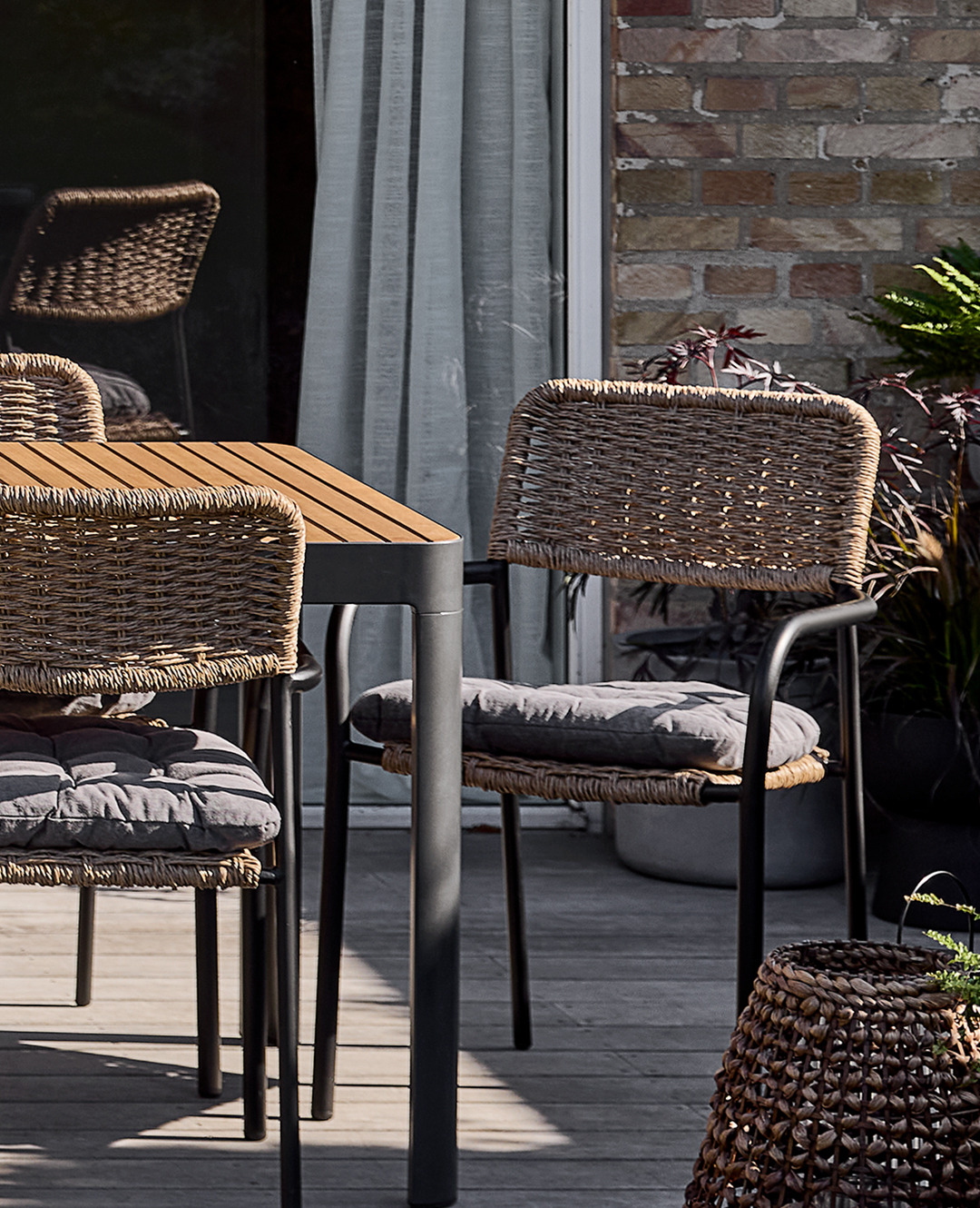 Садовий стілець з плетеними сидінням та спинкою біля столу на терасі