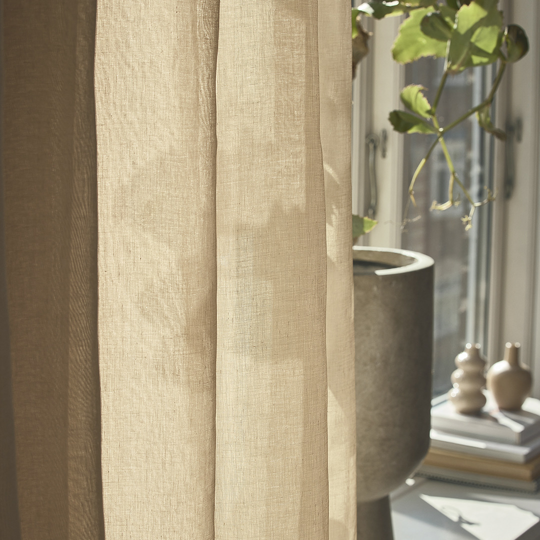 Бежева фіранка у вітальні, яка закриває підвіконня