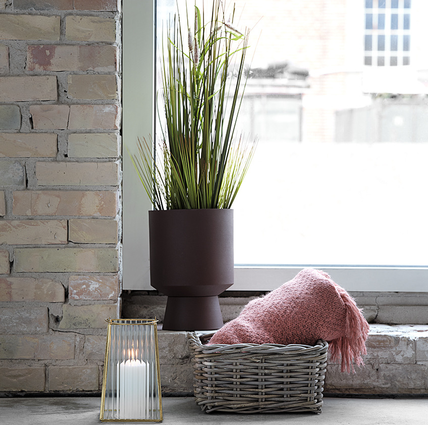 JOHN plant pot with GODSKE artificial plant, TOMMY lantern, and EIDE basket with a LINNEA throw in front of a window Plant pot with artificial plant, lantern, and basket with a pink throw in front of a window