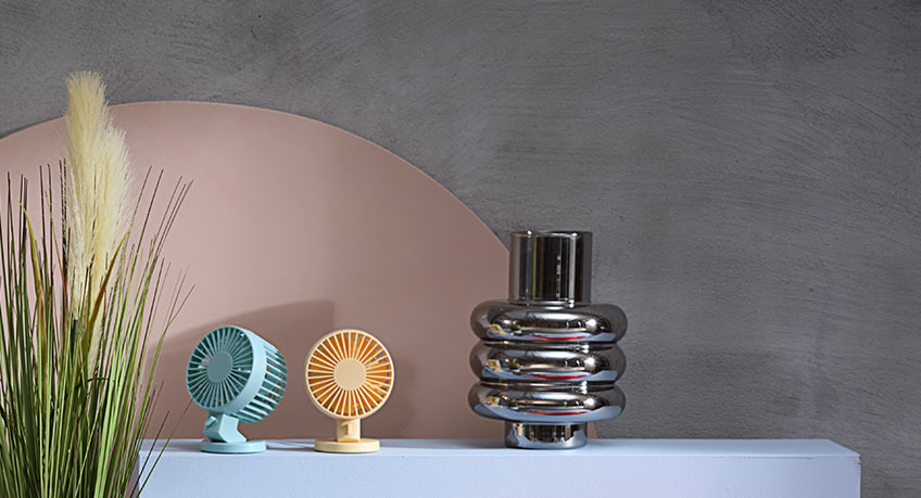 Two NIELSEN mini fans and MAGNIS metal vase beside GODSKE artificial plant Two mini fans and metal vase beside an artificial plant