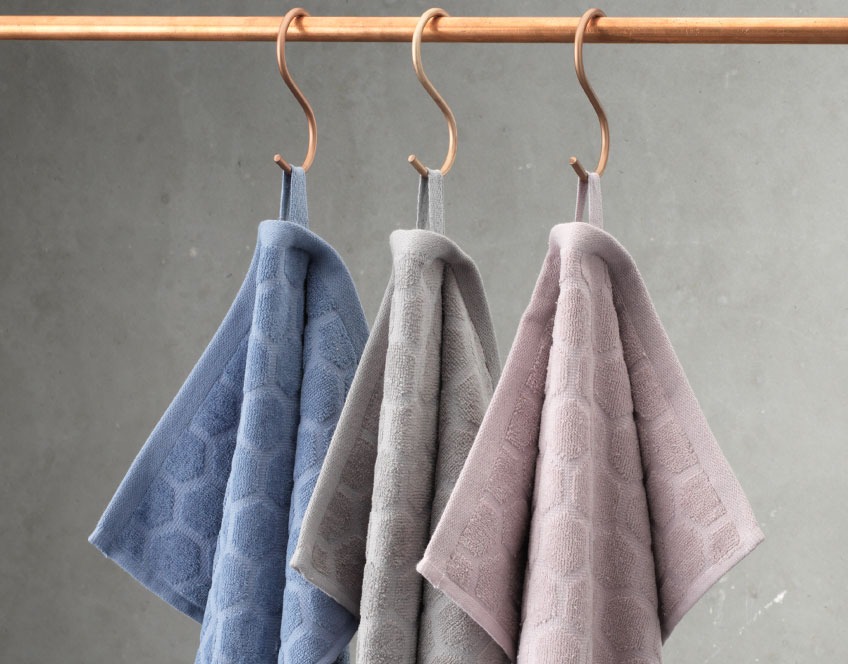 Hand towels in three colours hanging from a rail