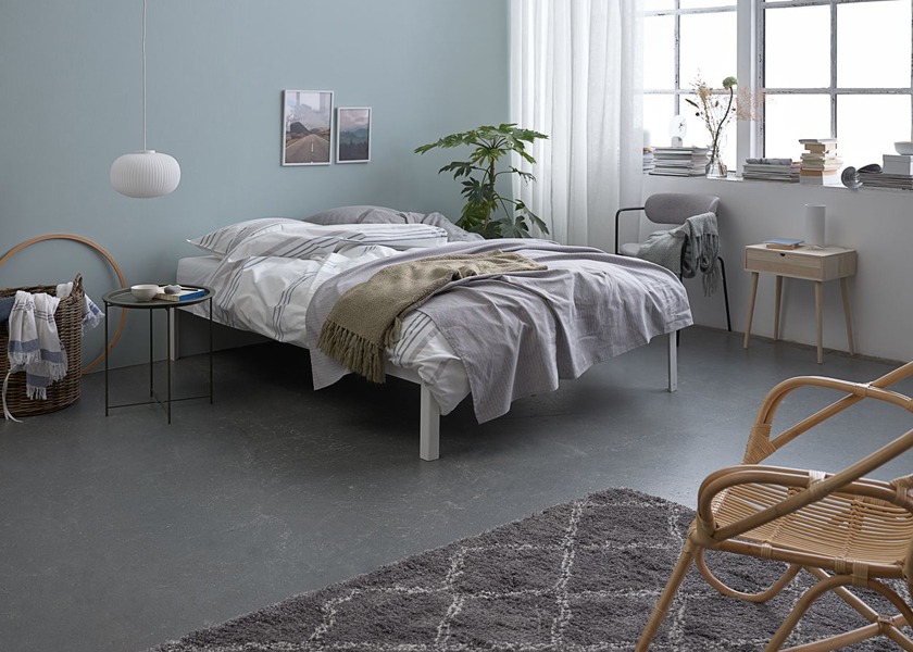 Спальна кімната з ліжком зі світлим комплектом постільної білизни, столиком, кріслом