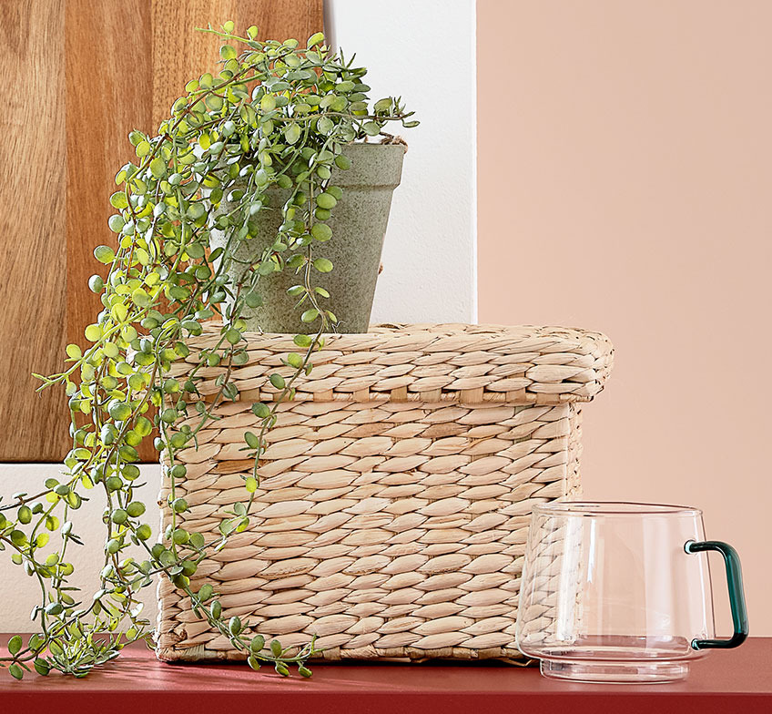 Джутовий кошик з рослиною та скляний кухлик поруч