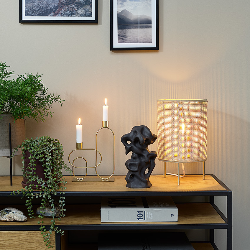 Горщики зі штучними квітами, свічник, декор та настільна лампа на тумбі під ТВ