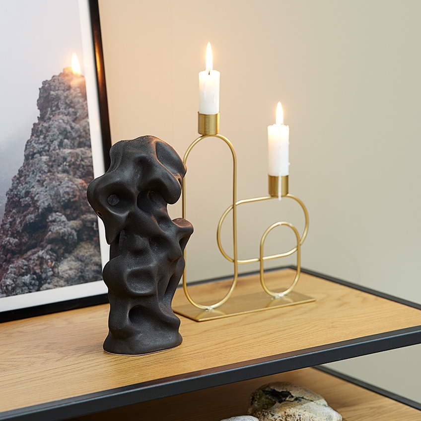 Позолочений свічник зі свічками та чорний декор на тумбі під ТВ
