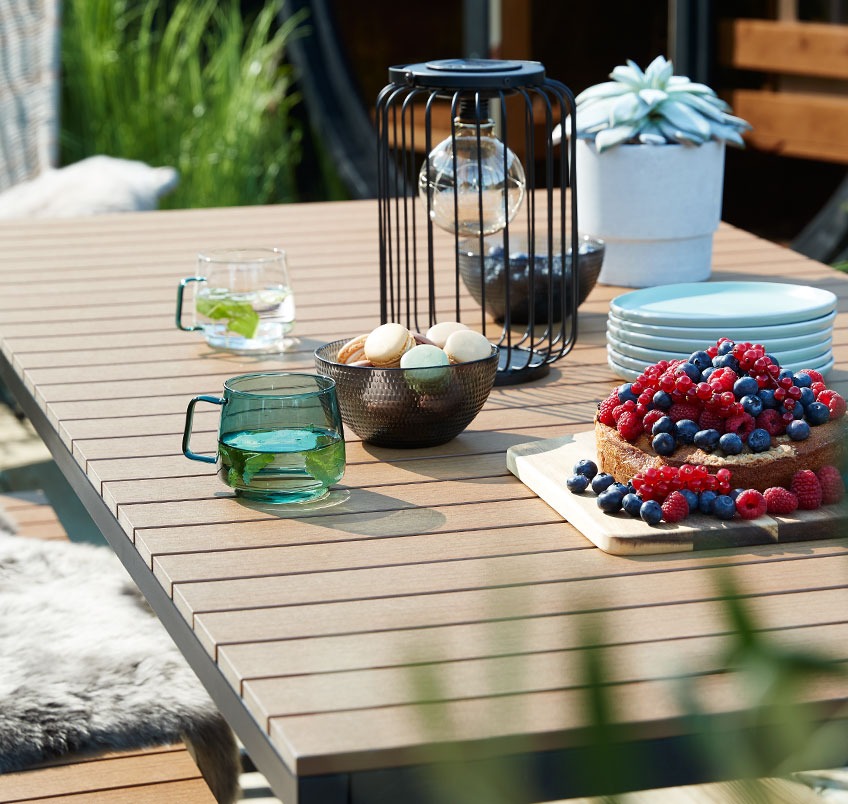 Садовий стіл на терасі з печивом, скляними кухликами та ліхтарями