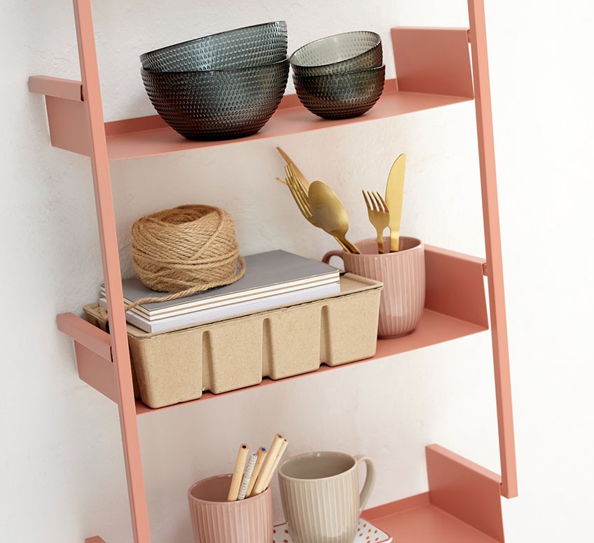 Настінні полиці персикового кольору зі скляними мисками, кухлями та коробом для зберігання