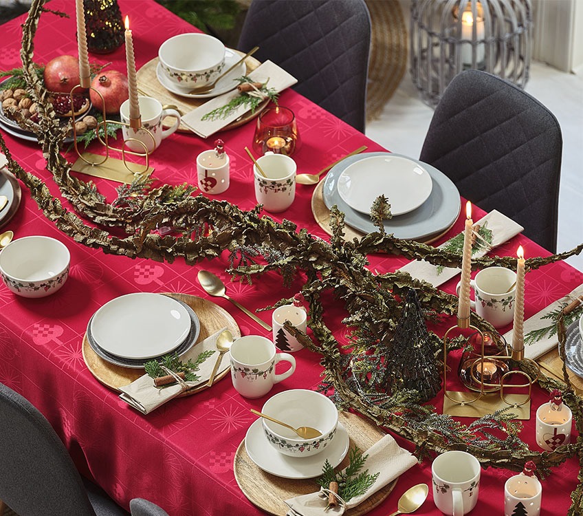 Святковий стіл з червоною скатертиною та золотими столовим набором