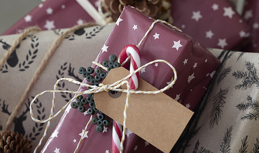 Різдвяний подарунок, загорнутий в папір і прикрашений цукерковою тростиною та перламутровими намистинами