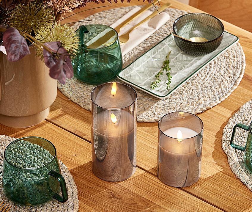 Обідній стіл з плетеними килимками, скляними мисками та кухлями