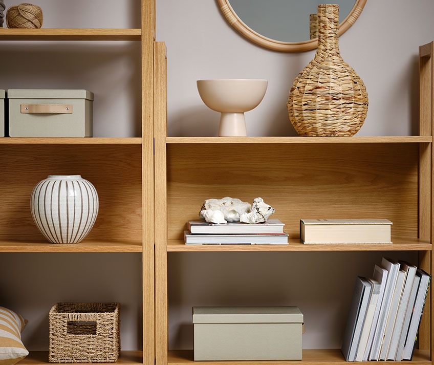 Книжкова шафа з плетеною вазою, мискою, ящиками для зберігання та іншими декоративними предметами