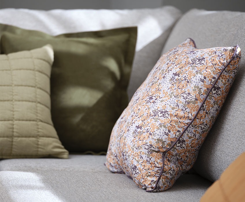 Сірий диван з квітковими та зеленими подушками