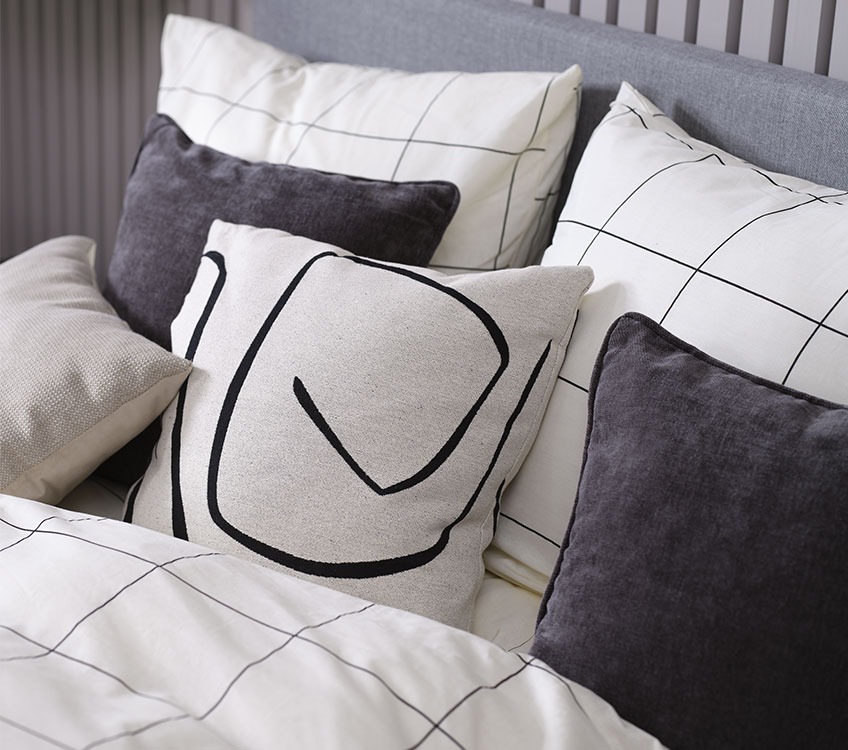 Спальня з біло-чорною постільною білизною і чорним і з декоративними подушками