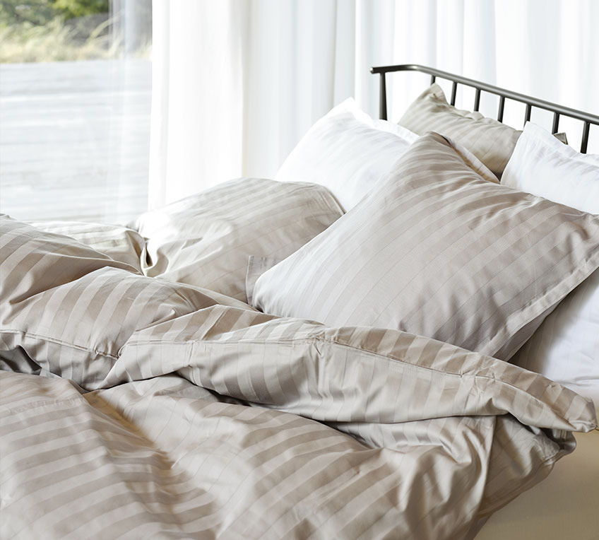 Ліжко з ковдрами та подушками із смугастою постільною білизною