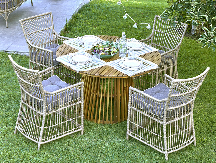 Круглий садовий стіл з центральною основою і чотири садові стільці на газоні 
