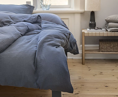 Синій комплект постільної білизни на ліжку біля приліжкової тумби з декором