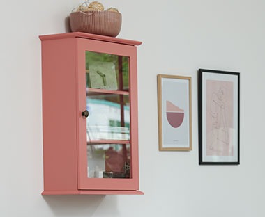Настінна шафка розевого кольору на три полиці з елементами декору всередині